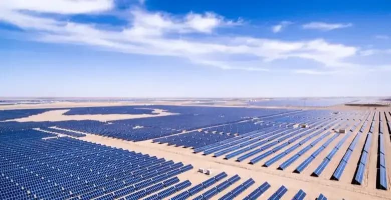 Rijen zonnepanelen in de woestijn onder een blauwe lucht met witte wolken
