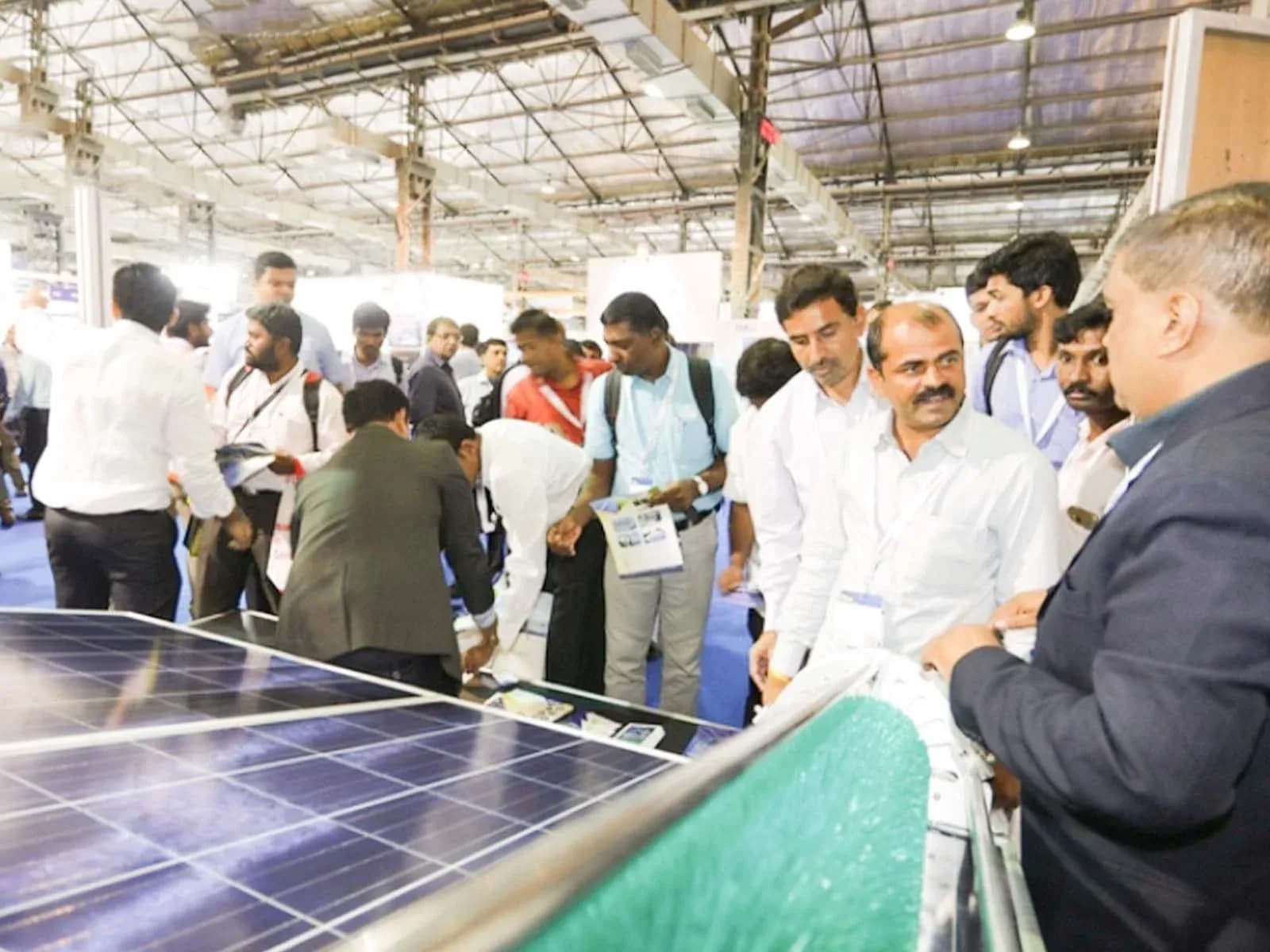 Besucher neben einem ausgestellten Solarmodul auf der Intersolar India