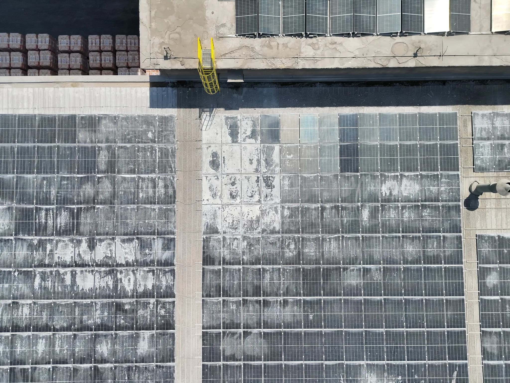 Aerial view of rooftop solar panels with extensive white surface deposits Aerial view of rooftop solar panels with extensive white surface deposits