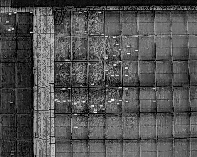 Grayscale thermal view of rooftop solar panels with scattered bright patches Grayscale thermal view of rooftop solar panels with scattered bright patches