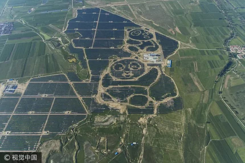 Luchtfoto van een zonnepark met twee pandavormige figuren Luchtopname van een zonnepaneelopstelling rond twee pandavormige figuren