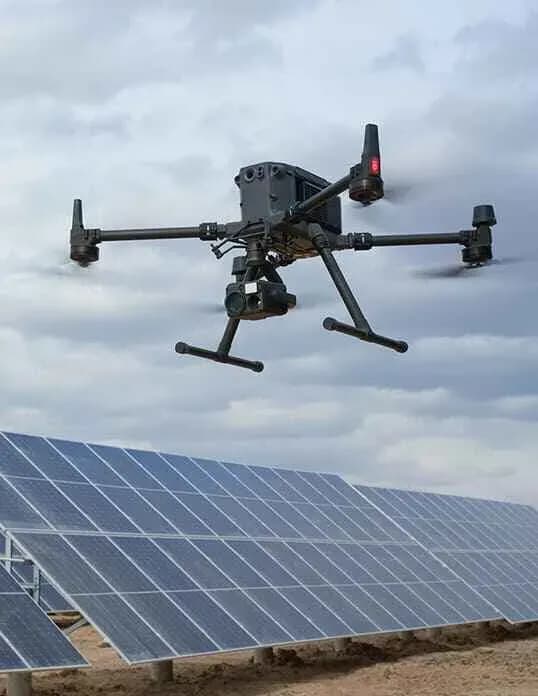 Drone in volo sopra pannelli solari sotto un cielo nuvoloso Drone in volo sopra pannelli solari sotto un cielo nuvoloso