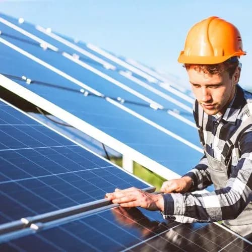 Arbeiten am Modul auf dem Dach Techniker mit Helm bei der Arbeit am Rand eines Solarmoduls auf dem Dach
